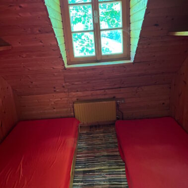 Die Schlafkoje im Dachraum weist eine Dachschräge mit lichtdurchflutetem Fenster auf.