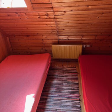 Die Schlafkojen haben jeweils 2 von einander getrennte Matratzen. Die Sonne strahlt durch das Fenster in der Dachschräge.